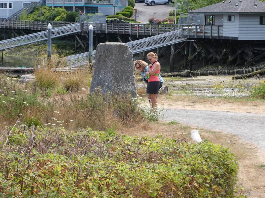 Two women stop to read a poem staked along a path near Donkey Creek in Gig Harbor.