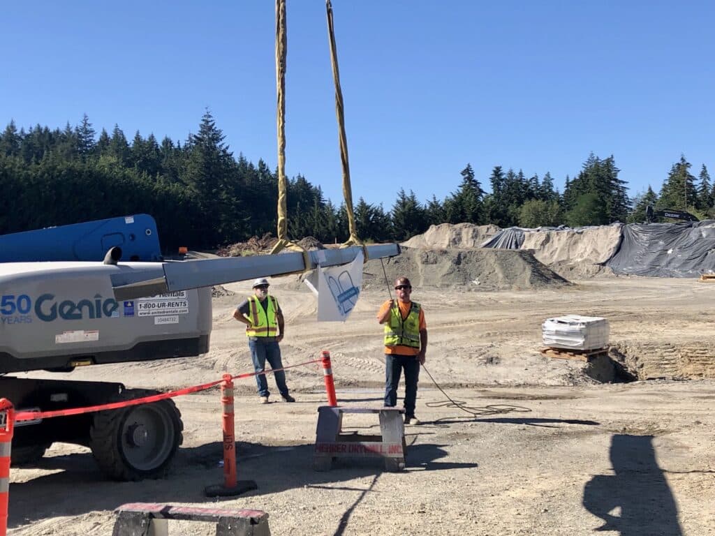 Workers guide the beam as a crane lifts it into place.