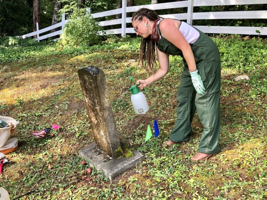 Tara Haag sprays a biological solution on a marker to remove growth.